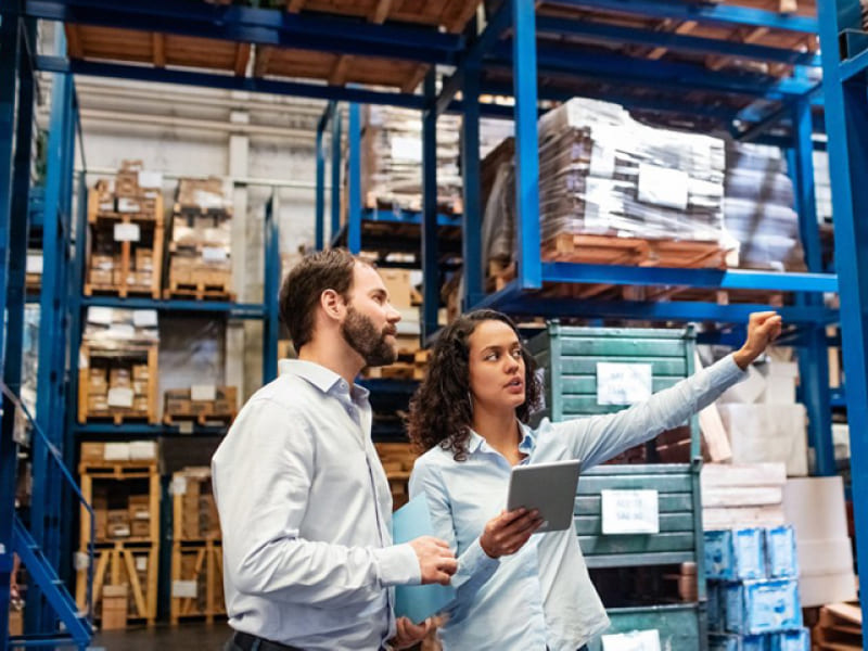 an image showing a lady and a man direct the operation of warehouse for reference